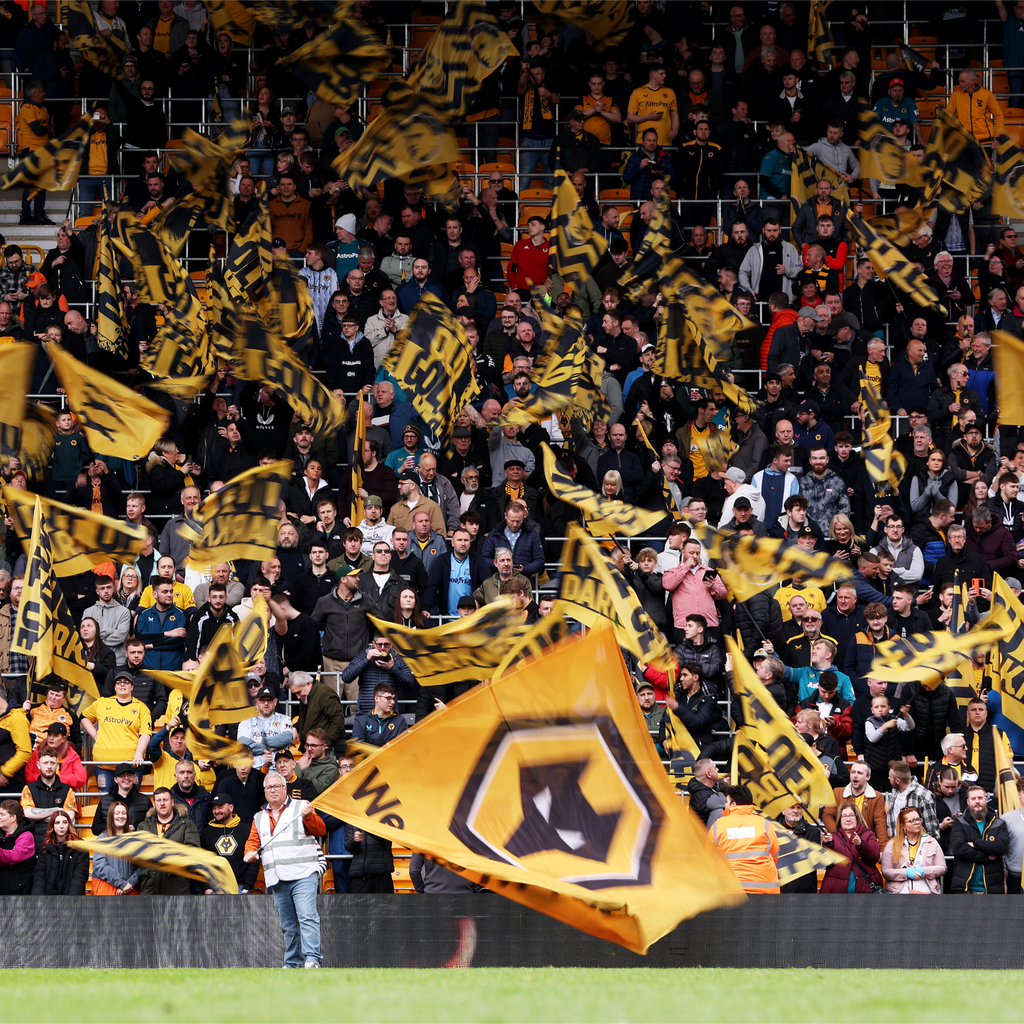 A large crowd of Wolverhampton Wanderers FC fans waving flags in the stands of Molineux football ground.