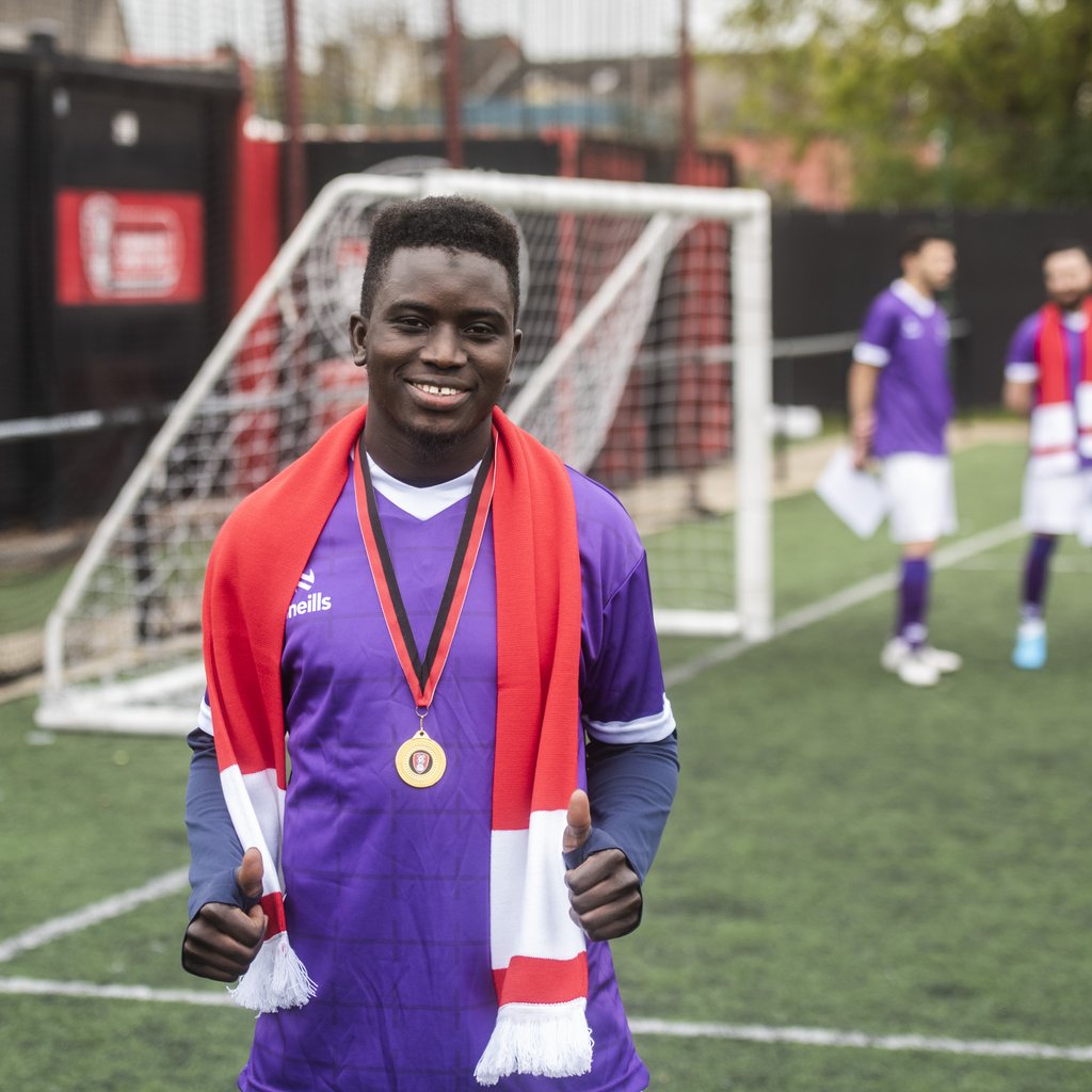 Fair Shot FC player Abdoulaye wearing a Rotherham United scarf