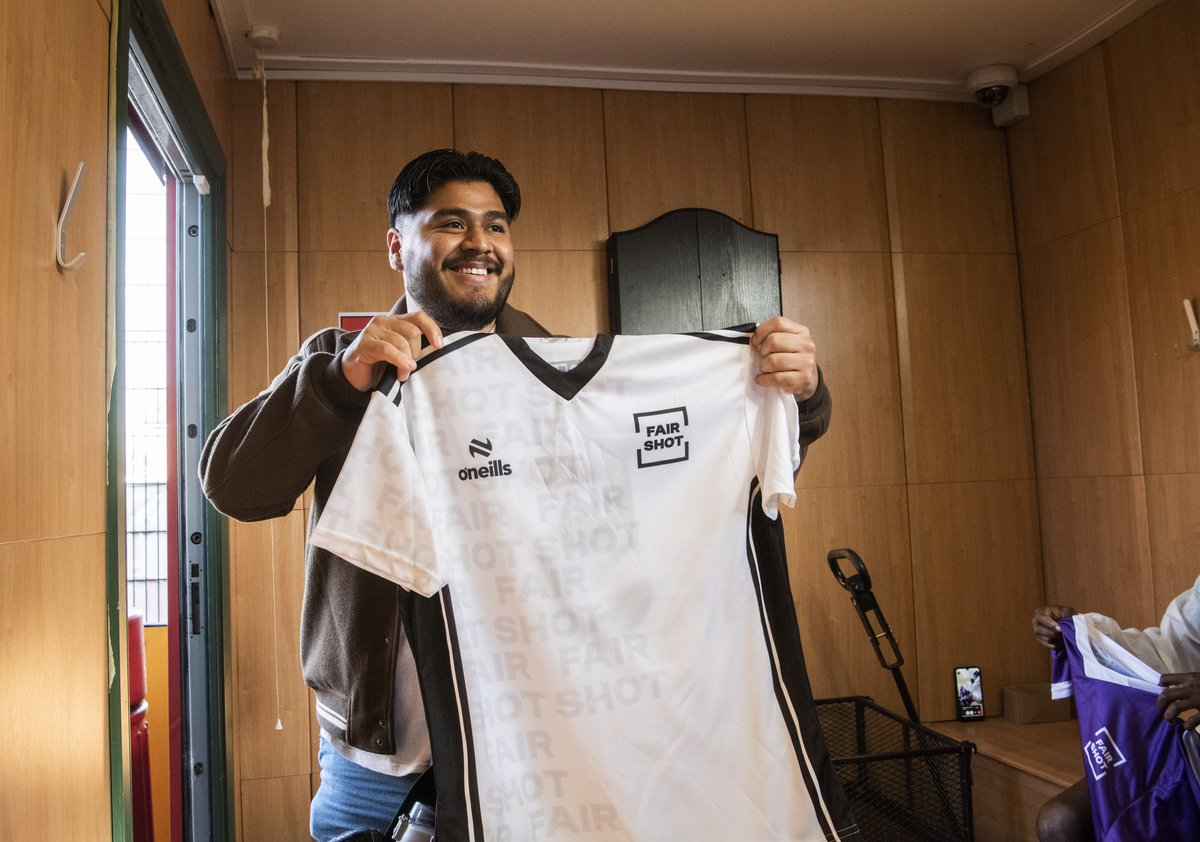 Alan, a Fair Shot FC player, holds up a Fair Shot football shirt